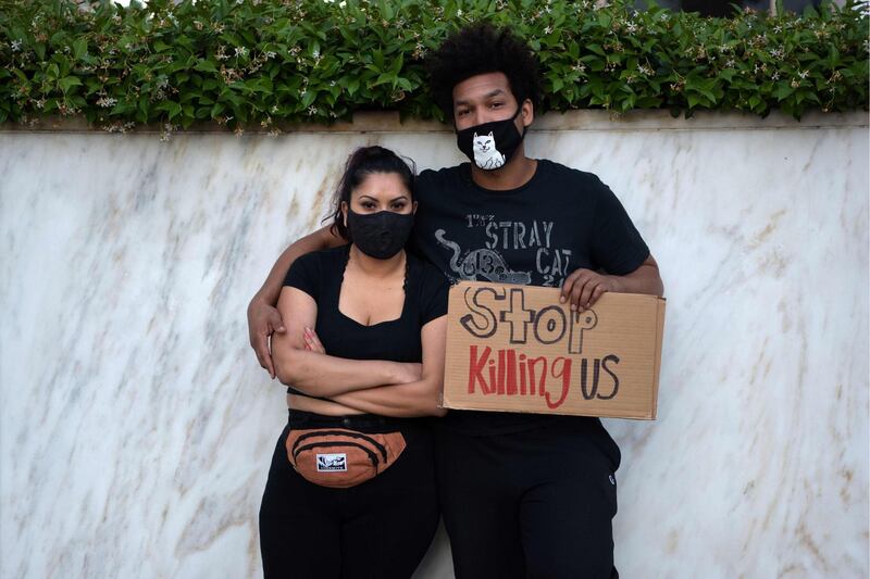 A couple poses with a sign as protesters gather in downtown Los Angeles. AFP