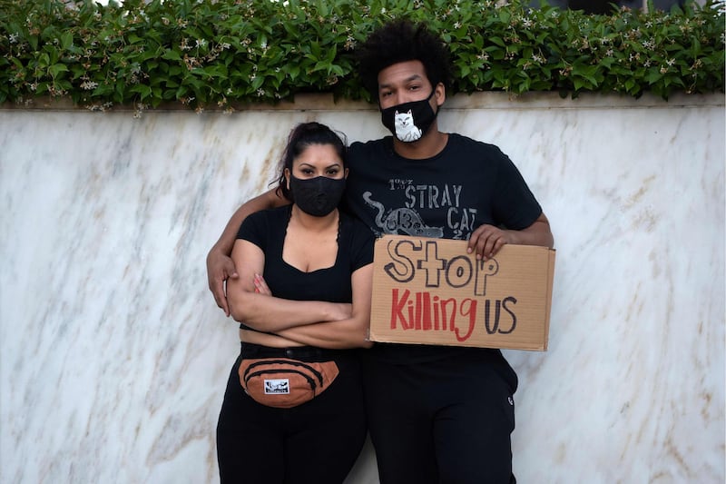 A couple poses with a sign as protesters gather in downtown Los Angeles. AFP