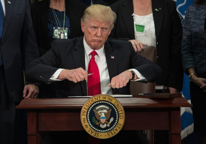 US president Donald Trump takes the cap off a pen to sign an executive order to start the Mexico border wall project at the Department of Homeland Security facility in Washington, DC, on January 25, 2017. Nicholas Kamm / AFP