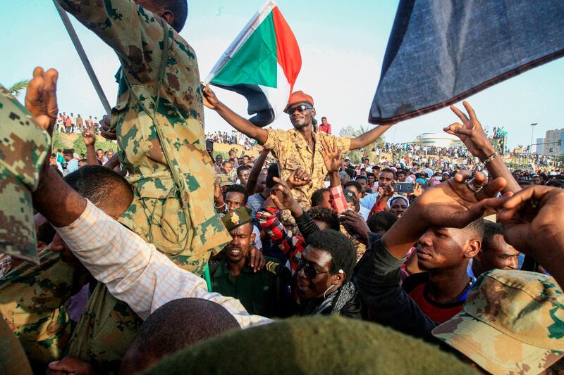 Sudanese protesters shout slogans as they carry soldiers during a rally outside the army complex in Sudan's capital Khartoum. AFP