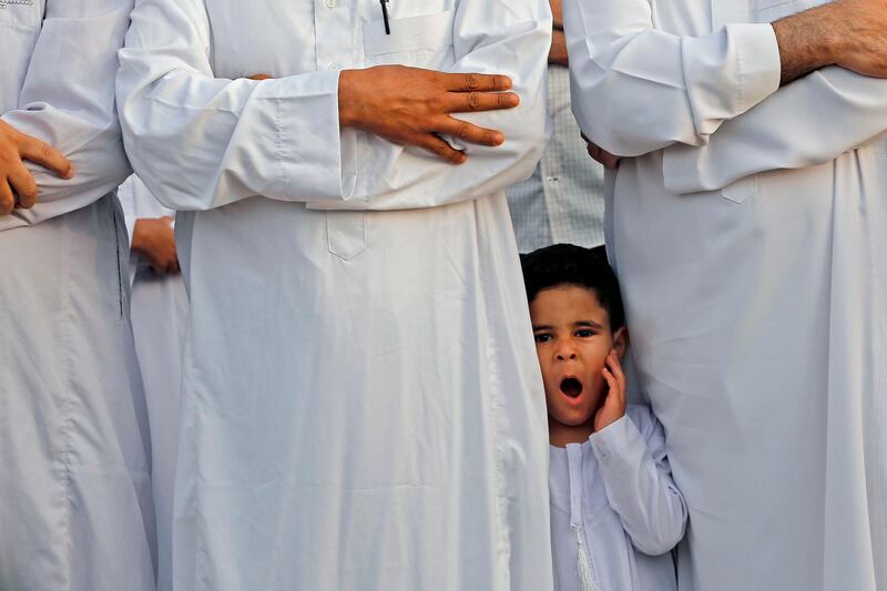 A Palestinian child stands next to a relative as adults perform morning prayer to celebrate Eid al-Fitr in Gaza City. AFP