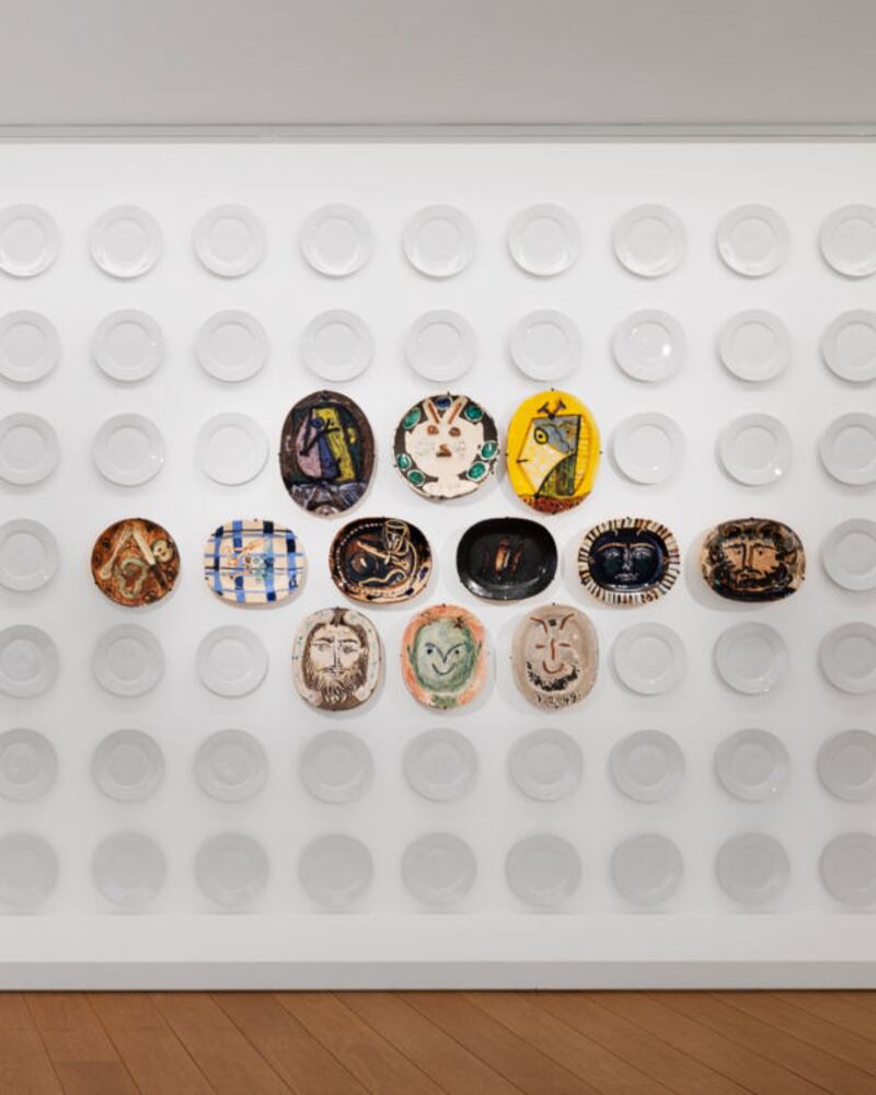 Picasso's painted plates positioned in the centre of a wall of plain plates