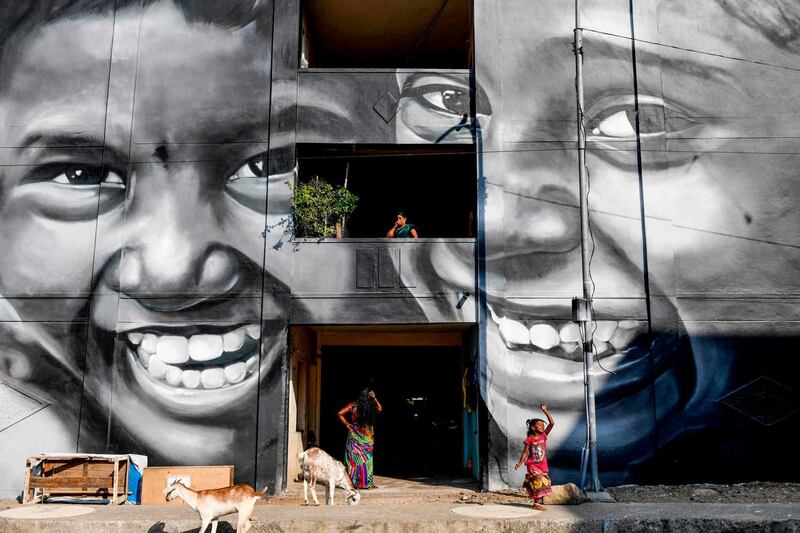 Residents walk past a mural painted on a building at a slum clearance board residential community in Chennai.  AFP