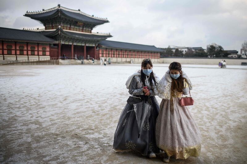 Visitors wear traditional hanbok dress as they walk on the grounds of Gyeongbokgung Palace after snowfall in Seoul. AFP