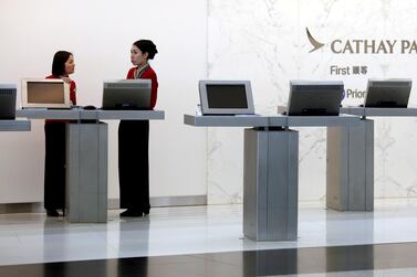 Attendants chat at the First Class counter of Cathay Pacific Airways at Hong Kong Airport. The airline said it would again honour its mis-priced tickets. Reuters