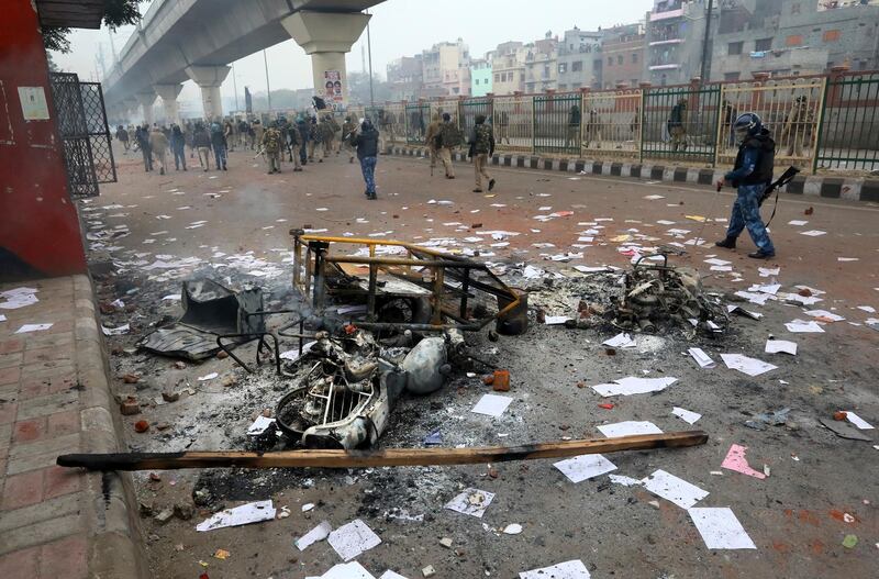 Policemen walk past a burnt motorcycles and a barricade during a protest against a new citizenship law at the Seelampur area of New Delhi. AP Photo