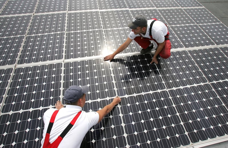 Workers perform maintenance on solar panels on the roof of a warehouse in Buerstadt, Germany. Getty Images