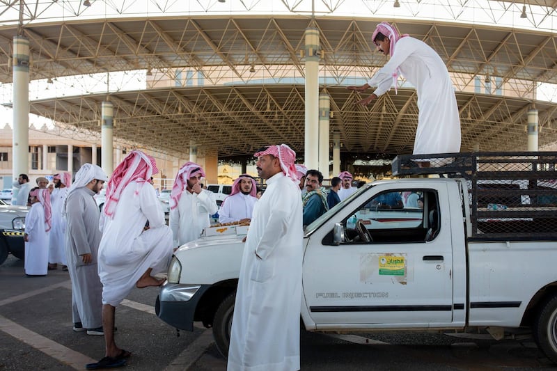 A trader stands on a pickup truck to sell boxes of dates at the local market in Buraidah, Saudi Arabia.  Bloomberg