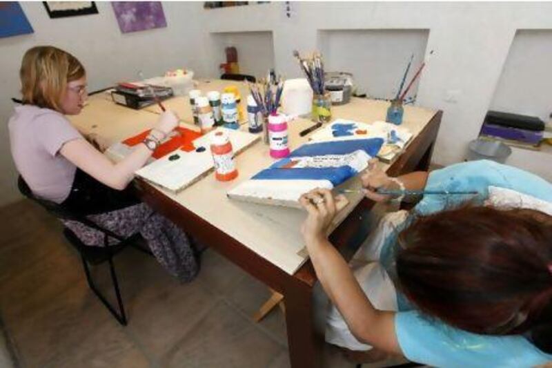 Artists with special needs Rebecca Hayday, 19, left, from the UK and Anjali Anju, 25, from India paint the fabric to be used for the dress for a Dubai fashion school's show. Jeffrey E Biteng / The National