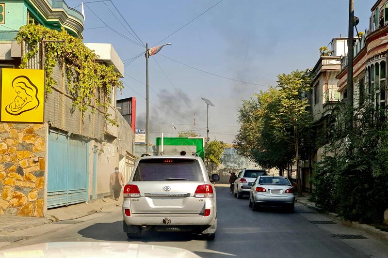 Vehicles drive along a road against the backdrop of smoke rising. AFP