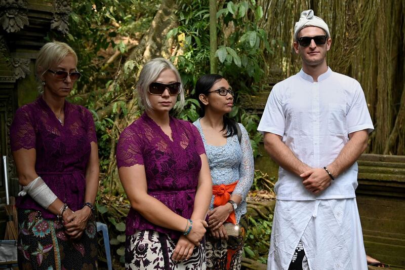 Czech nationals Sabina Dolezalova (2nd L) and her boyfriend Zdenek Slouka (R) wait to take part in a ritual at the Beji Temple, located inside a monkey sanctuary in Ubud on Indonesia's resort island of Bali on August 15, after a disrespectful online video they posted went viral. The Czech couple slammed for disrespecting a Balinese temple took part in a ritual purification ceremony on August 15, after their antics sparked warnings that boorish tourists may be kicked out of the Indonesian holiday island. / AFP / SONNY TUMBELAKA
