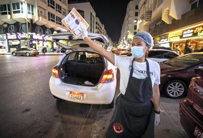 Abu Dhabi, United Arab Emirates, October  12, 2020.  Khalidiya by night article by Saeed Saeed on restaurants, café's on Al Yahar Street.  Al Shatir Hassan Restaurant employee, Beth Lopez,  offers motorists the menu for a quick bite.
Victor Besa/The National
Section:  NA
Reporter:  Saeed Saeed