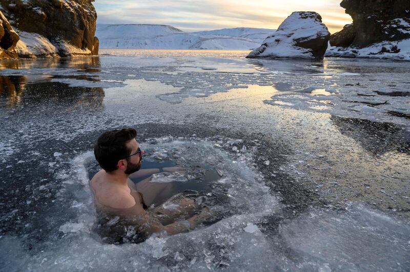 A participant baths in the waters of an ice-covered lake in southwestern Iceland during a seminar on February 1, 2020 in Kleyfarvatn, near Reykjavik. - Using slow, deliberate movements and deep breathing, bathers immerse themselves in the waters of an ice-covered lake in southwestern Iceland. The temperature above the frozen lake of Kleifarvatn, one of country's deepest, is minus six degrees Celsius (21.2 degrees Fahrenheit). (Photo by Halldor KOLBEINS / AFP)