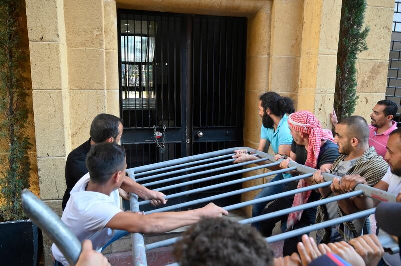 Protesters try to uproot the gate at the Lebanese Ministry of Economy. EPA