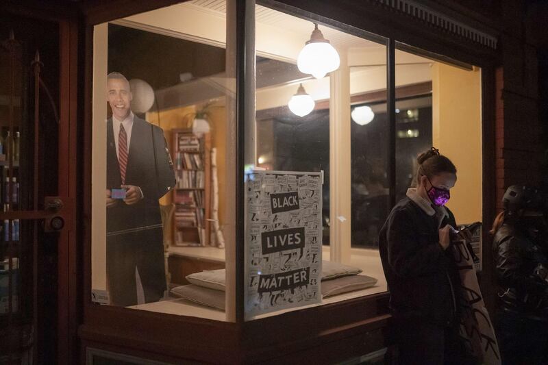 A protester checks election results on her phone in front of a cutout of former President Barack Obama during a Black Lives Matter march in Portland, Oregon. After a record-breaking early voting turnout, Americans head to the polls on the last day to cast their vote for incumbent U.S. President Donald Trump or Democratic nominee Joe Biden in the 2020 presidential election. AFP