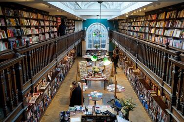 Customers wearing face covering browse for books inside the re-opened Daunt Books independent bookshop in London. AFP