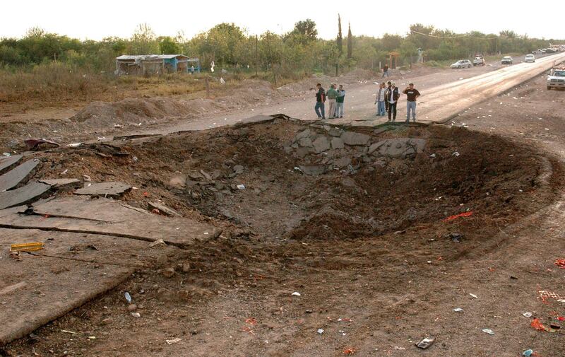 Reporters stand next to a crater, measuring 20 metres (65 feet) in diameter, which was caused by a blast, in a road near Monclova, in the northern state of Coahuila, September 10, 2007. Dozens of people died when a trailer-truck loaded with highly flammable chemicals exploded in a road accident in northern Mexico, local media reported on Monday. REUTERS/Sergio Rodriguez/Zocalo (MEXICO)