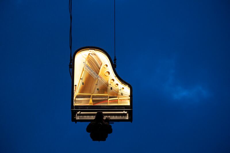 Artist Alain Roche plays piano while hanging from a crane in Munich. Audiences wearing headphones listened to the piano mixed with sounds of awakening nature captured by 40 microphones in Bavaria and Switzerland as the sun rose, in a project entitled When The Sun Stands Still. EPA