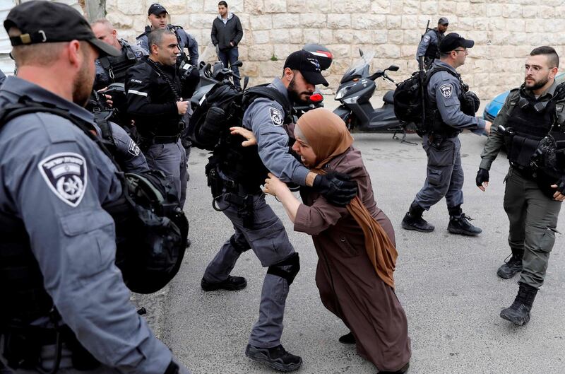 TOPSHOT - An Israeli policeman pushes back a Palestinian woman outside the Old City of Jerusalem after Israeli forces closed the entrance to al-Aqsa mosque compound on March 12, 2019. / AFP / AHMAD GHARABLI

