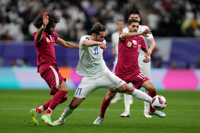 Uzbekistan's Oston Urunov, centre, competes for the ball with Qatar's Akram Afif, left, and Hasan Al Haydos. AP
