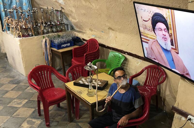 A man smokes a hookah as he watches Lebanon's Hezbollah leader Sayyed Hassan Nasrallah speak on television inside a coffee shop in the port city of Sidon, Lebanon July 12, 2019. REUTERS/Ali Hashisho