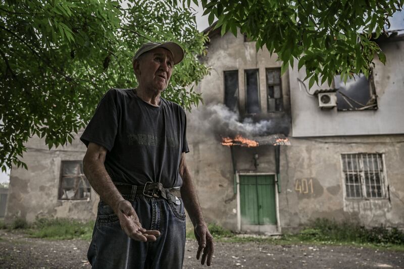 A man in front of the apartment building where he lives as it burns after a shelling in Lysychansk, in the eastern Ukrainian region of Donbas. AFP