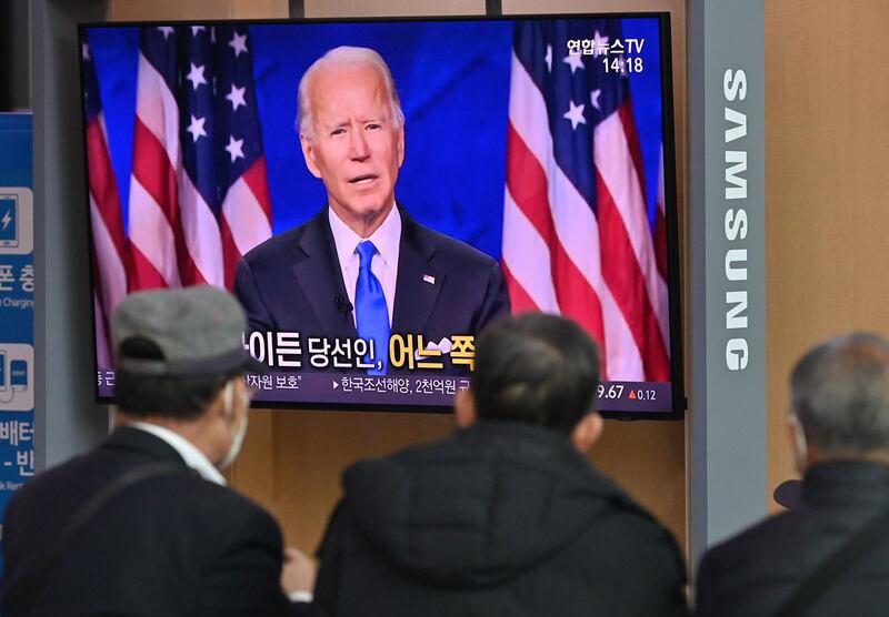 People watch a television news programme reporting on the US presidential election showing an image of US President-elect Joe Biden, at a railway station in Seoul on November 9, 2020. / AFP / Jung Yeon-je
