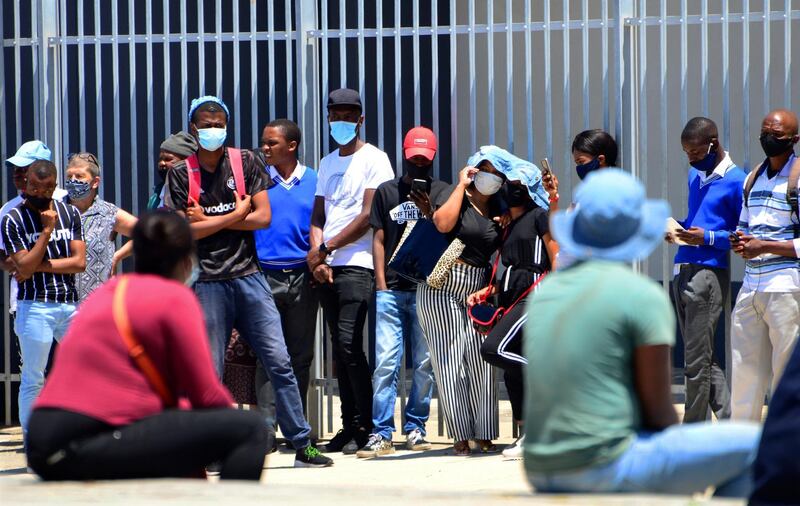 Without practising social distancing people queue outside home affairs offices for document in Port Elizabeth, South Africa, Friday, Nov. 13, 2020. The Eastern Cape Province is seeing a surge in cases of coronavirus and has recorded the highest number of COVID-19-related deaths in the country. (AP Photo/Theo Jeptha)