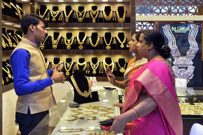 Indian customers look at gold jewellery at a stall in the Asia Jewels Fair 2017 held in Bangalore on August 11, 2017.  / AFP PHOTO / MANJUNATH KIRAN