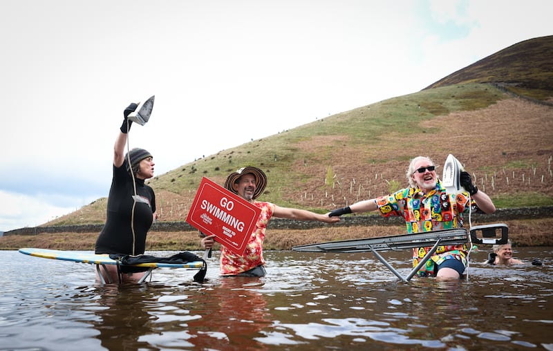 Members of the wild swimming group Sheffield Outdoor Plungers take part in ‘extreme ironing’ during a mass trespass swim at Kinder Reservoir, in Derbyshire. EPA