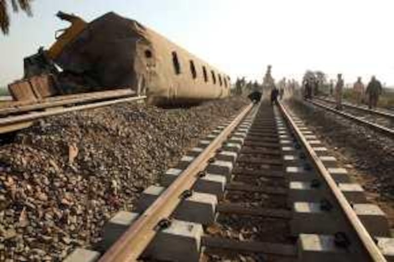 Bystanders watch as police and workers lay new track next to the wreck of Saturday's train accident in the southern Giza town of Ayyat on October 25, 2009. Victoria Hazou *** Local Caption ***  VH_traincrash.011.JPG