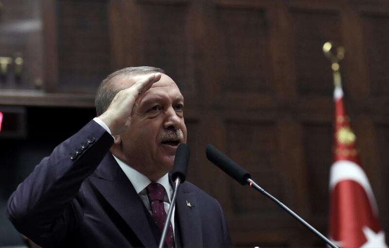Turkish President Recep Tayyip Erdogan gives a military salute as he addresses his ruling party legislators at the Parliament, in Ankara, Wednesday, Oct. 30, 2019. Erdogan said Turkey would not hesitate to relaunch its operation if the Syrian Kurdish fighters do not fully evacuate the 30 kilometer (19 mile) area in northeastern Syria or continue attacks against Turkish troops.(AP Photo/Burhan Ozbilici)