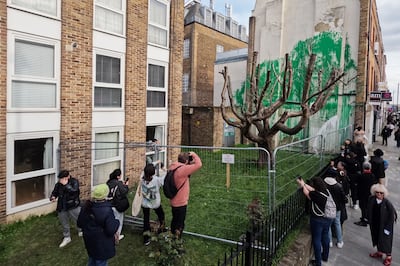 Members of the public look at a mural by the artist Banksy after it was defaced with white paint, in the Finsbury Park area of London. Getty Images