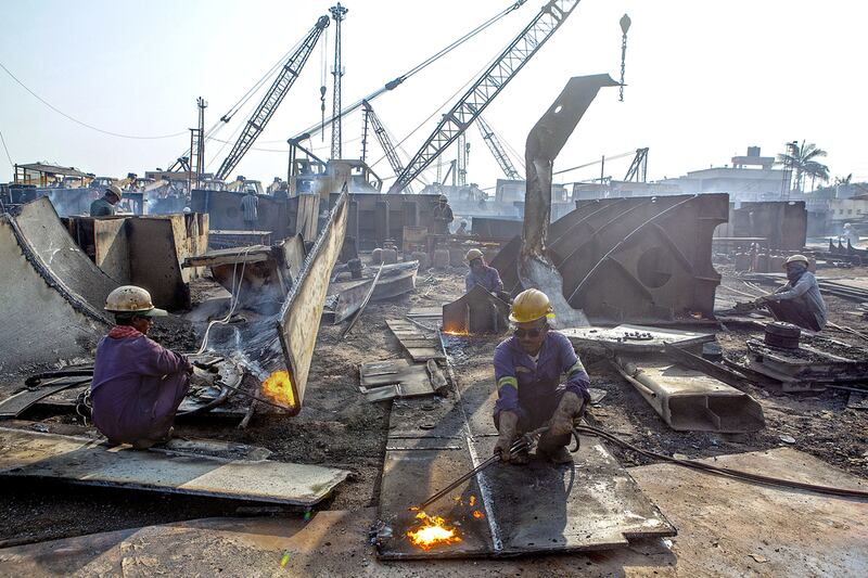 Workers cut through metal parts at a ship-breaking yard at Alang. Subhash Sharma for The National