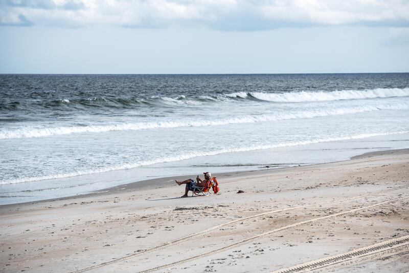 A person sits on the beach after people evacuated in Carolina Beach, North Carolina. EPA