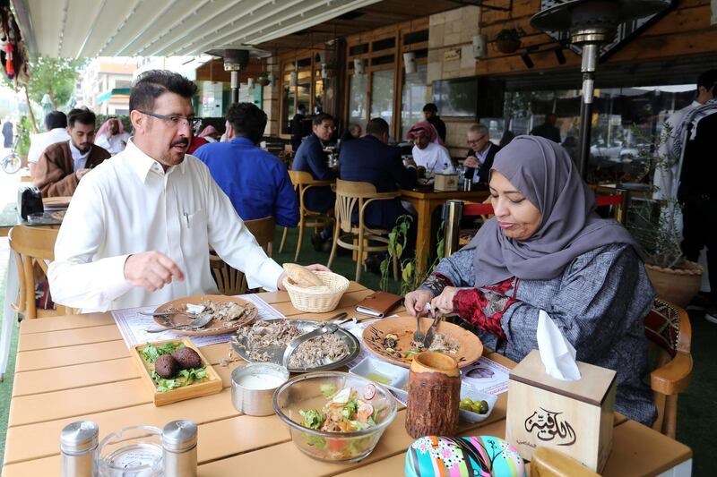 Men and women eat food in a restaurant in Riyadh. Reuters