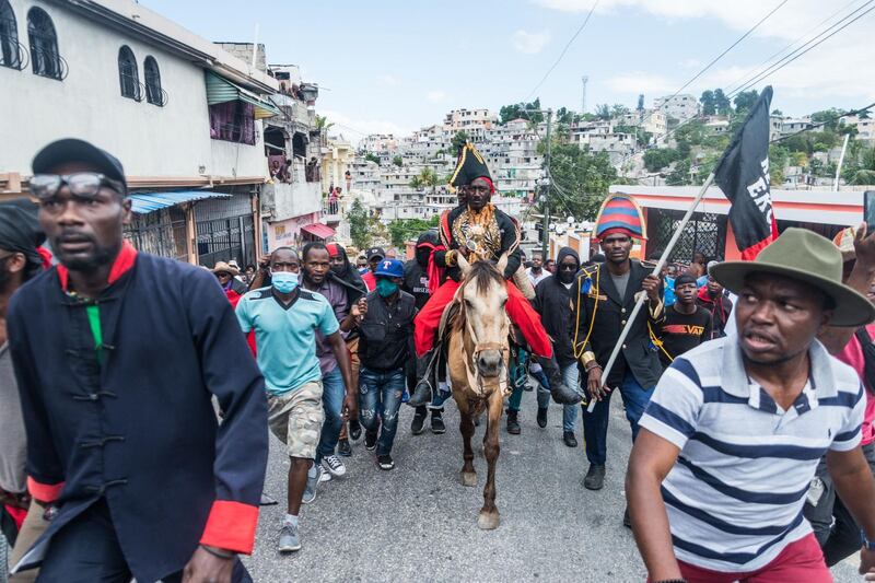 Former senator Jean Charles Moise, leader of the Pitit Desalin Party, accompanies Haitian protesters on horseback as they march through the streets of Port-au-Prince to denounce a year of President Jovenel Moise's rule by decree. AFP