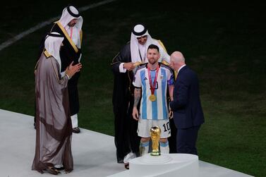 Qatar's Emir Sheikh Tamim bin Hamad al-Thani (C top) wraps an abaya around Argentina's forward #10 Lionel Messi next to FIFA President Gianni Infantino (R) at the end of the Qatar 2022 World Cup final football match between Argentina and France at Lusail Stadium in Lusail, north of Doha on December 18, 2022.  - Argentina won in the penalty shoot-out.  (Photo by Odd ANDERSEN  /  AFP)