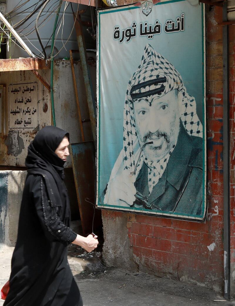 A refugee walks in front of a poster showing the late Palestinian leader Yasser Arafat in the camp Burj al-Barajneh, south of the capital Beirut. AFP