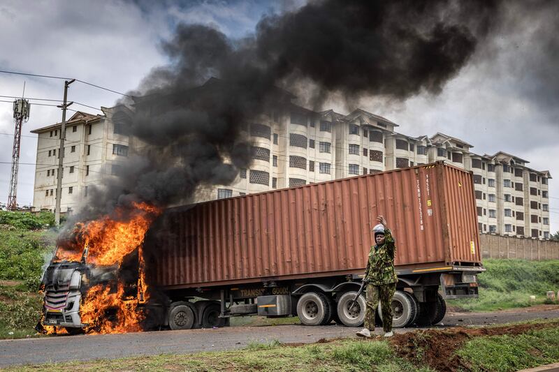 A Kenyan police officer stands next to a lorry set on fire in Nairobi during a protest against the cost-of-living crisis and last year's election results. AFP