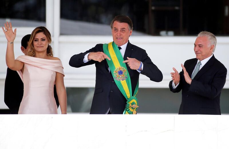 Mr Bolsonaro points at the presidential sash during his inauguration ceremony. Reuters