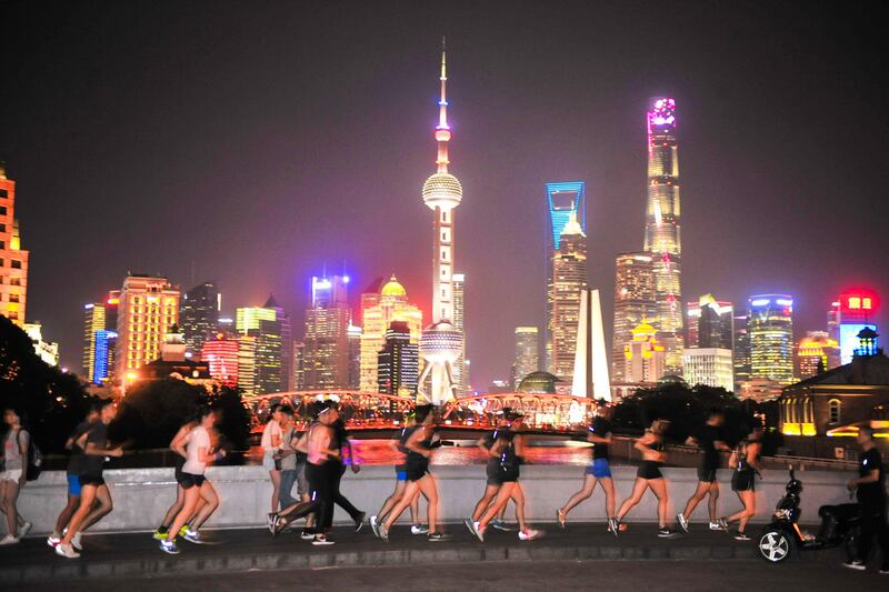This photo taken on July 28, 2017 shows people running at night in Shanghai. 
A growing number of young, educated, urban Chinese are shrugging off the myriad hazards to keep fit through serious running and the number of marathons and running events in the country is mushrooming. / AFP PHOTO / STR / China OUT / TO GO WITH AFP STORY LIFESTYLE-CHINA-RUNNING-HEALTH-POLLUTION,FEATURE BY PETER STEBBINGS