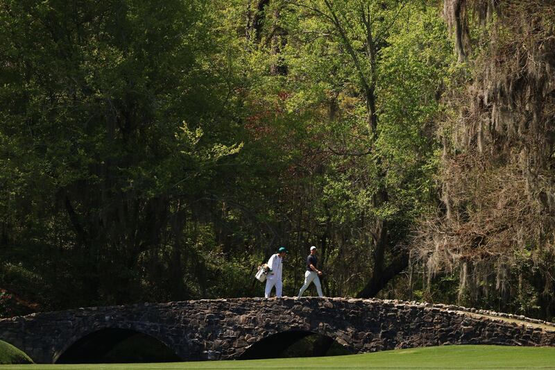 Rory McIlroy and his caddie Harry Diamond walk across the Nelson Bridge on the 13th hole during a practice round prior to the Masters. AFP