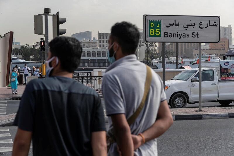 DUBAI, UNITED ARAB EMIRATES. 25 FEBRUARY 2021. COVID - 19 Standalone. Deira souk during the time of Covid. Two mean wait to cross Baniyas str while wearing masks. The are was previously under police lockdown due to it's high cases of covid-19. (Photo: Antonie Robertson/The National) Journalist: Nick Webster. Section: National.