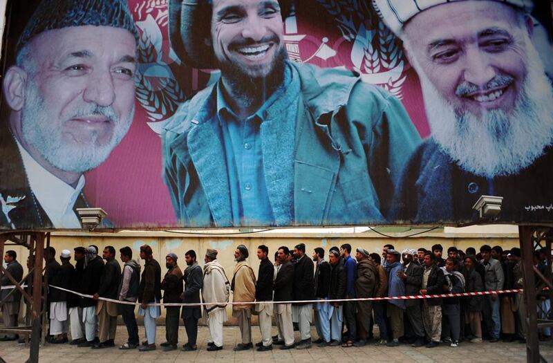 Afghan residents wishing to vote line up underneath a billboard showing images of Afghan President Hamid Karzai (L) and of deceased Afghan figures Burhandin Rabani (R) and Ahmad Shah Massoud (C) outside a polling station in Mazar-i-Sharif on April 5, 2014. Afghan voters went to the polls Saturday to choose a successor to President Hamid Karzai, braving Taliban threats in a landmark election held as US-led forces wind down their long intervention in the country. Afghanistan’s third presidential election brings an end to 13 years of rule by Karzai, who has held power since the Taliban were ousted in a US-led invasion in 2001, and will be the first democratic handover of power in the country’s turbulent history.  Farshad Usyan / AFP