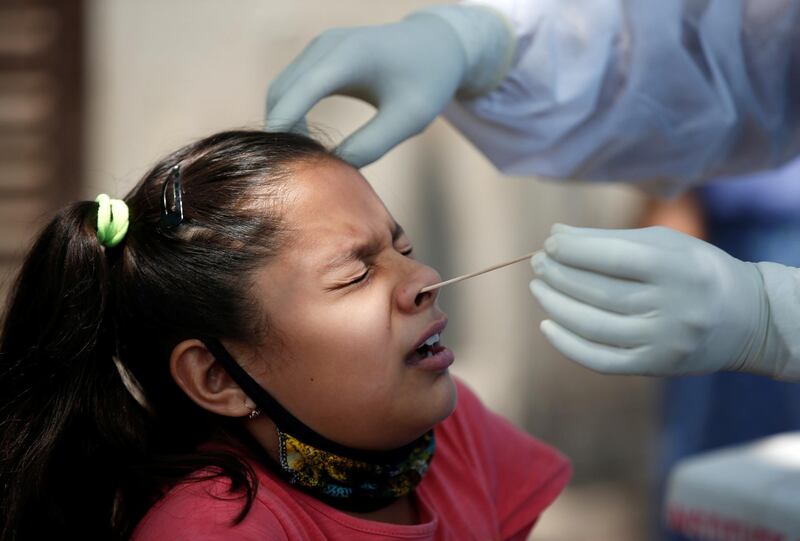 A girl reacts as a doctor wearing protective gloves takes a swab from her to test for the coronavirus disease at a residential area in Ahmedabad, India, Reuters