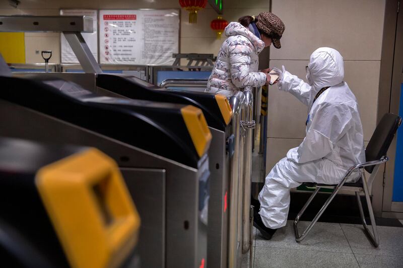 A worker wearing a hazardous materials suit gives directions to a passenger at a subway station in Beijing. AP Photo