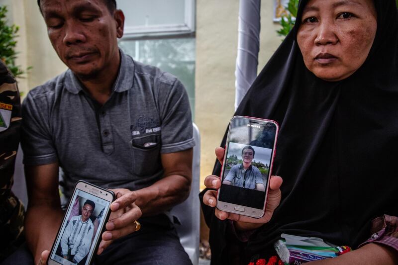 Epi and Yenny Syamsul show pictures of their son who was aboard the flight. Getty Images