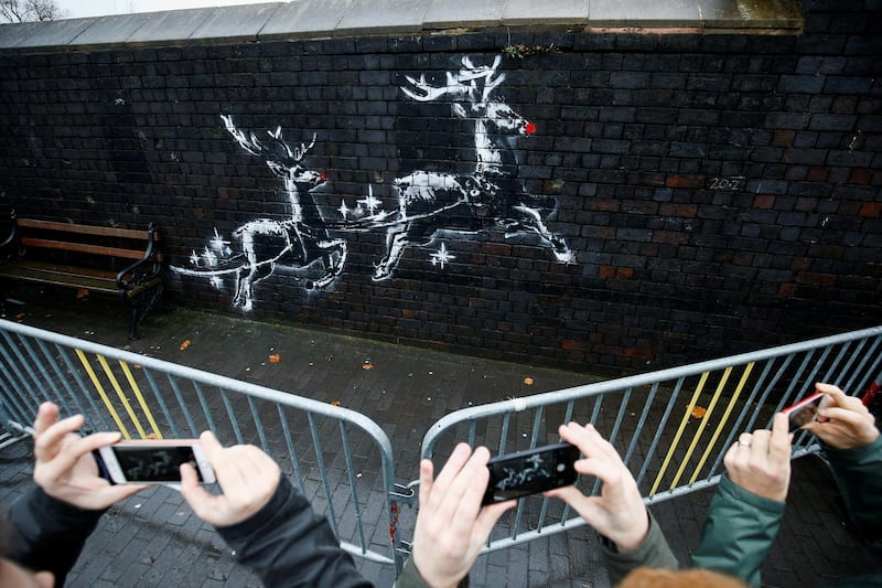 People gather round a new mural by the street artist Banksy in Birmingham, Britain, December 10, 2019.  REUTERS/Henry Nicholls  NO RESALES. NO ARCHIVES
