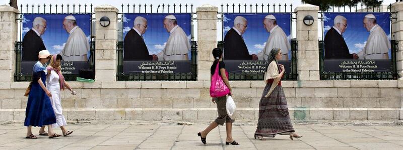Tourists walk towards the Church of the Nativity, the accepted birthplace of Jesus Christ, in the West Bank town of Bethlehem on Wednesday, passing banners showing Pope Francis and the Palestinian president, Mahmoud Abbas. The Argentine-born pontiff will arrive in Bethlehem on May 24, 2014. Jim Hollander / EPA

